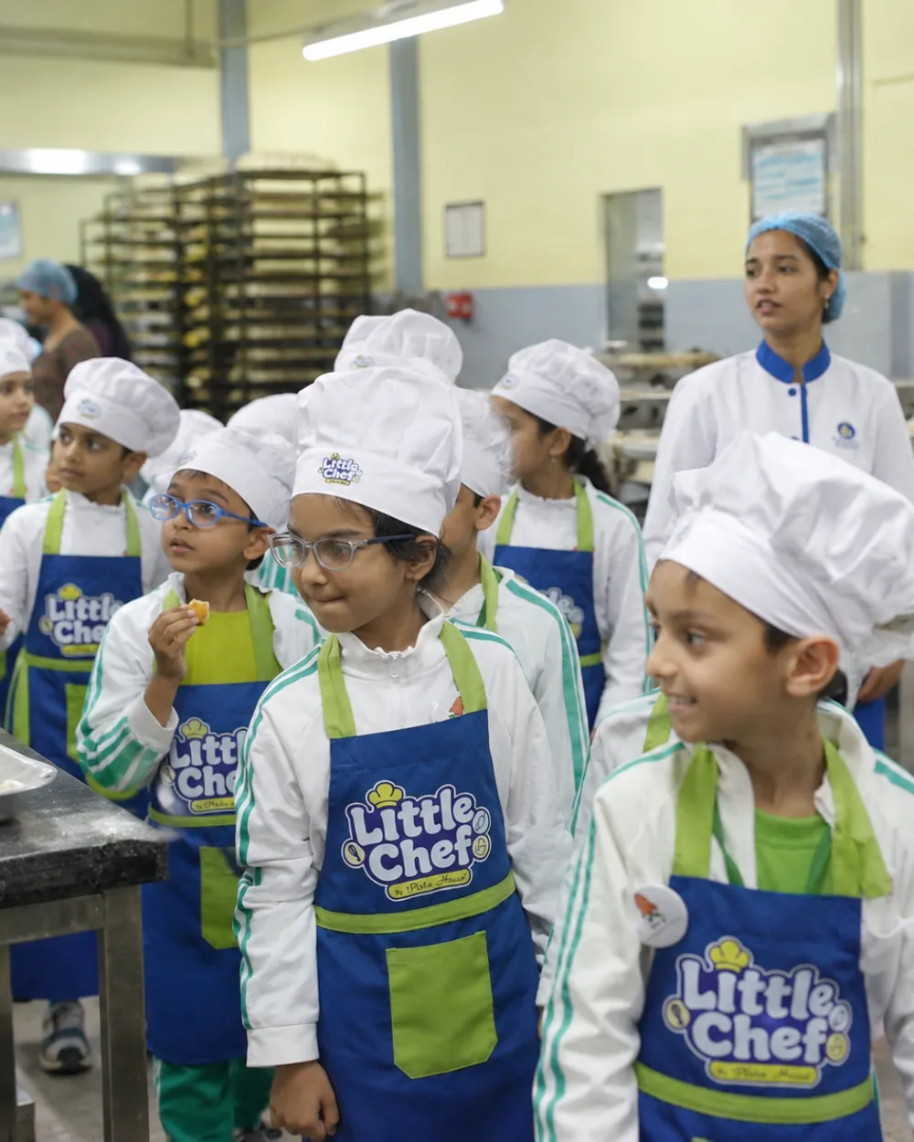 Little Chefs in aprons and chef caps tasting fresh biscuits inside the Pista House bakery